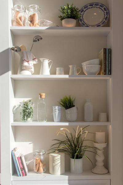 4 layer white wooden bowl and bottles on the shelf
